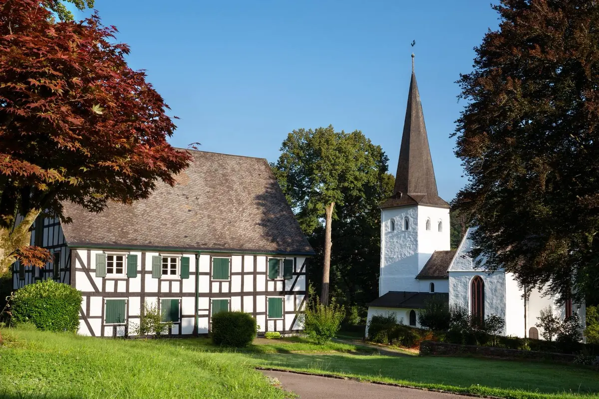 Fachwerkhaus und weiße Kirche mit hohem Turm im Grünen Fachwerkhaus und weiße Kirche mit hohem Turm im Grünen