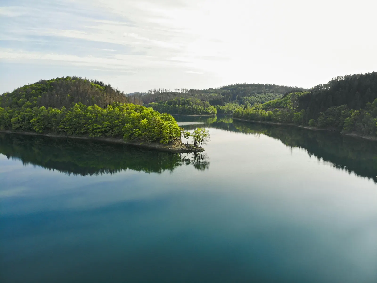Talsperre mit bewaldeter Landzunge aus der Luft, ruhige Wasserfläche Talsperre mit bewaldeter Landzunge aus der Luft, ruhige Wasserfläche