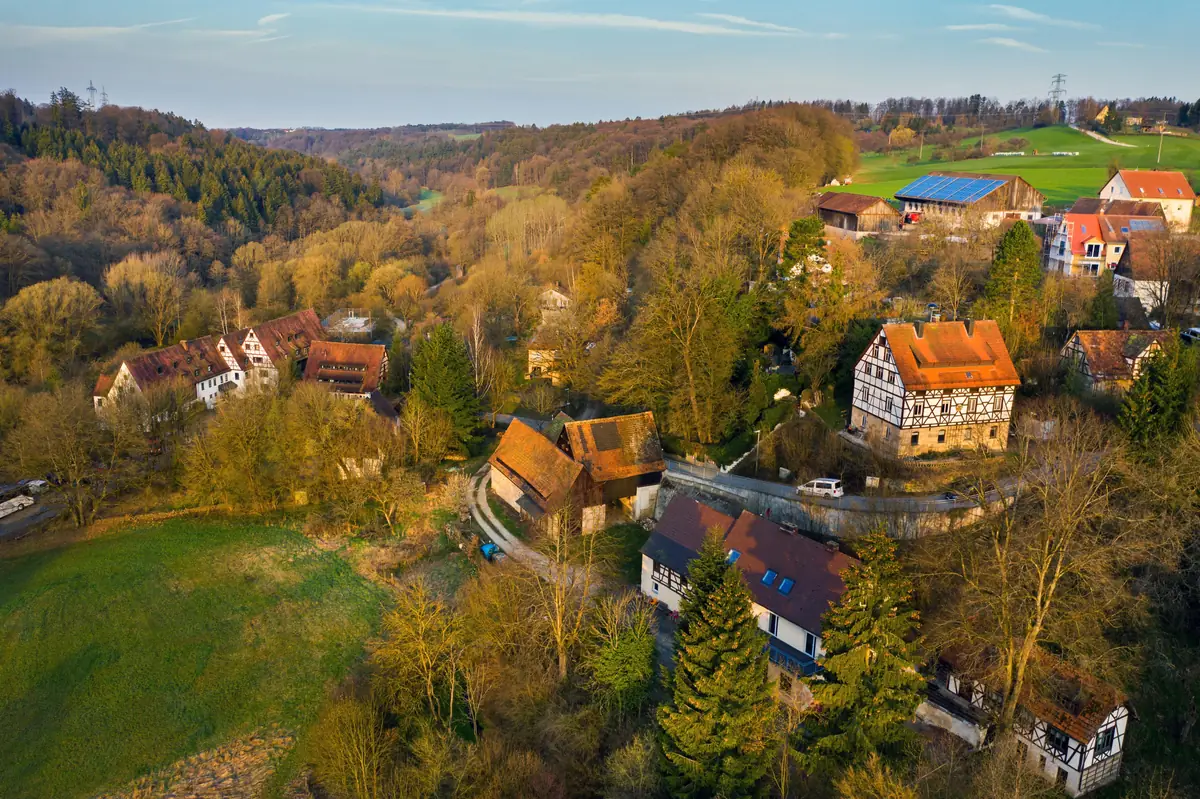 Fachwerkhäuser und Wiesen in einem bewaldeten Tal aus der Luft Fachwerkhäuser und Wiesen in einem bewaldeten Tal aus der Luft