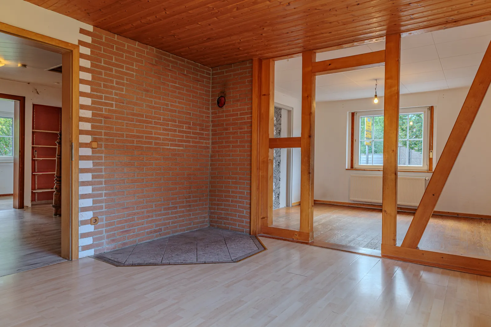 Wohnzimmer mit Klinkerwand, Holzdecke und Fachwerk-Raumteiler Wohnzimmer mit Klinkerwand, Holzdecke und Fachwerk-Raumteiler