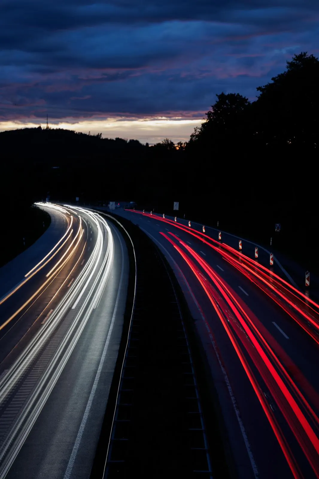 Langzeitaufnahme einer Straße bei Dämmerung mit weißen und roten Lichtspuren
